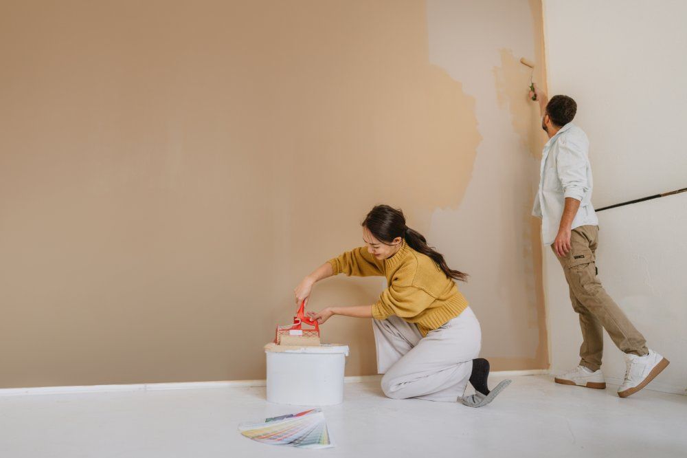 Paar, das während der Renovierung seines Hauses gemeinsam eine Wand streicht